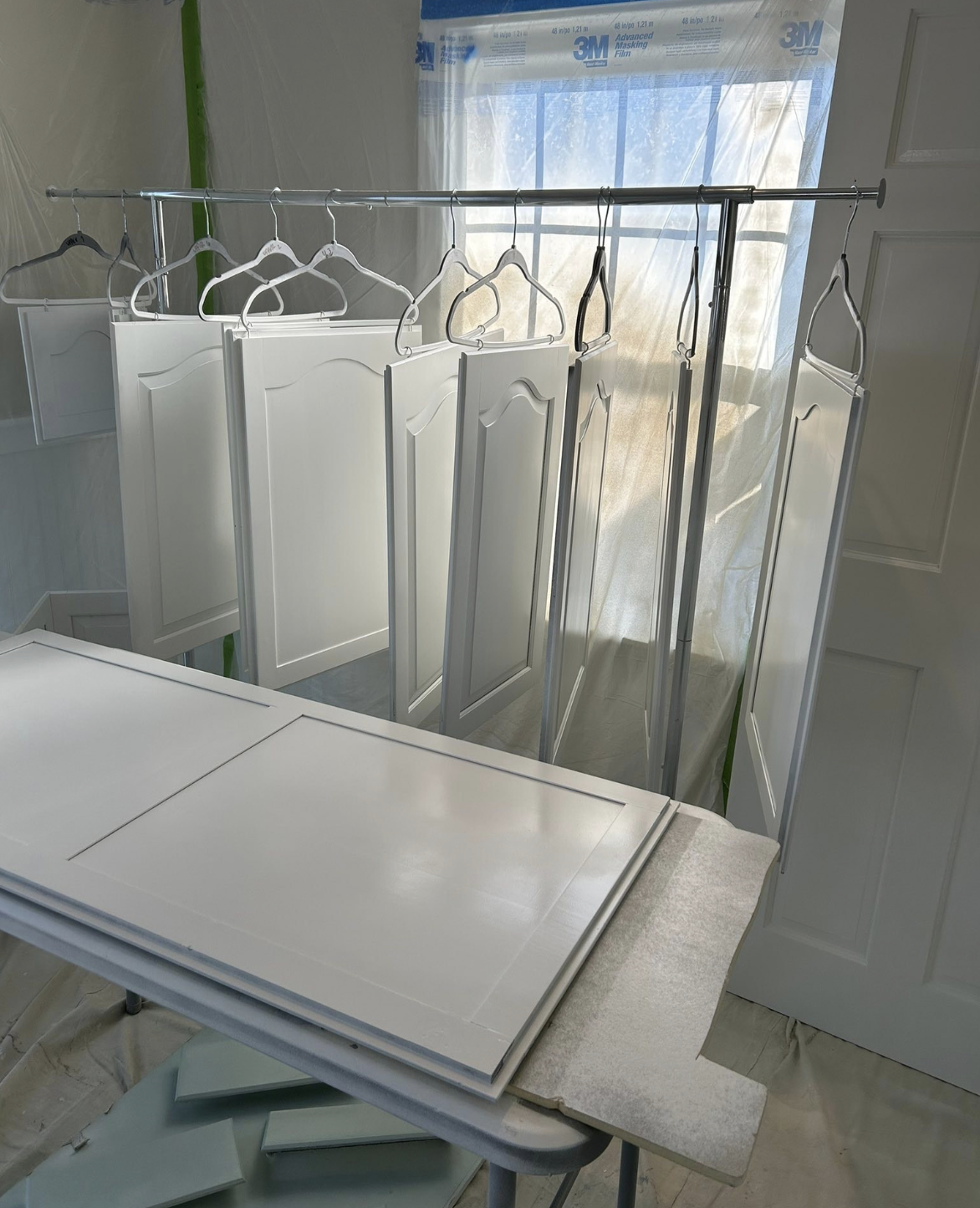 Freshly sprayed white cabinet doors hung to dry in a controlled spray area